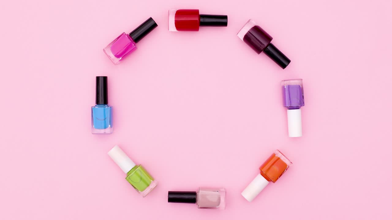 botellas coloridas de esmalte de uñas se mueven en círculo en el tema rosa. detener el movimiento