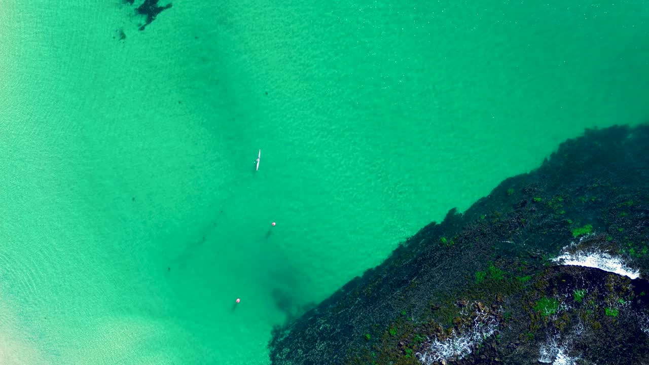 Drone aerial landscape of kayaker paddle along sandbar channel inlet and floating buoy with ocean seafloor and rocky reef Norah Head beach bay Central Coast Australia travel adventure leisure sports