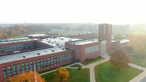 aerial pullback reveals american flag at large brick school building