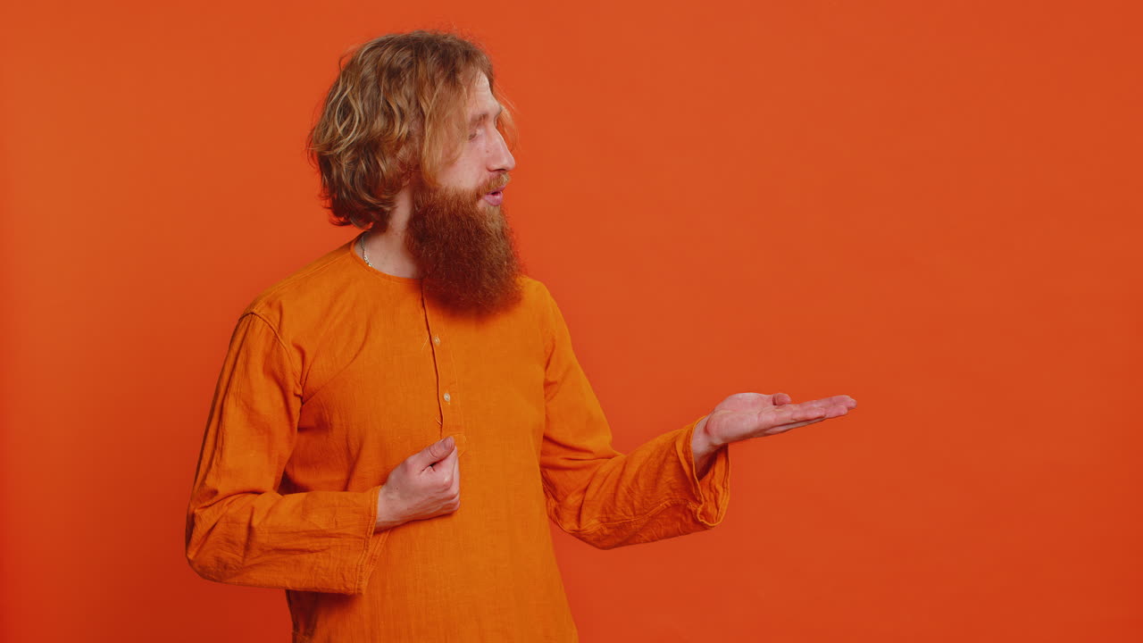 Young man showing thumbs up and pointing at right on blank space place for your advertisement logo
