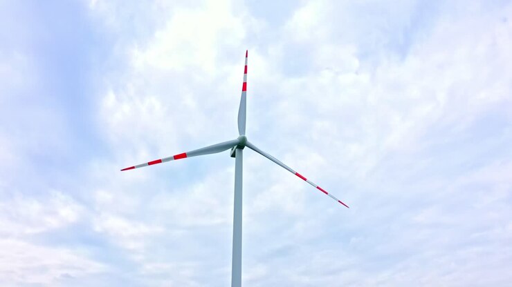 Roterende vindmølle på en smuk himmel med hvide skyer.