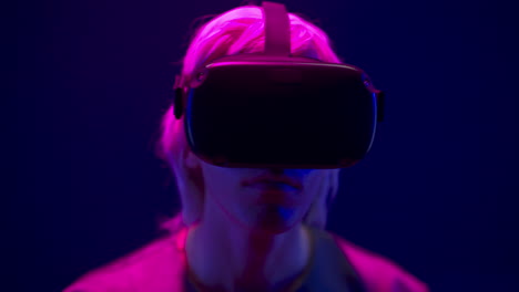 focused man watching vr headset in neon light closeup. guy enjoying 3d movie