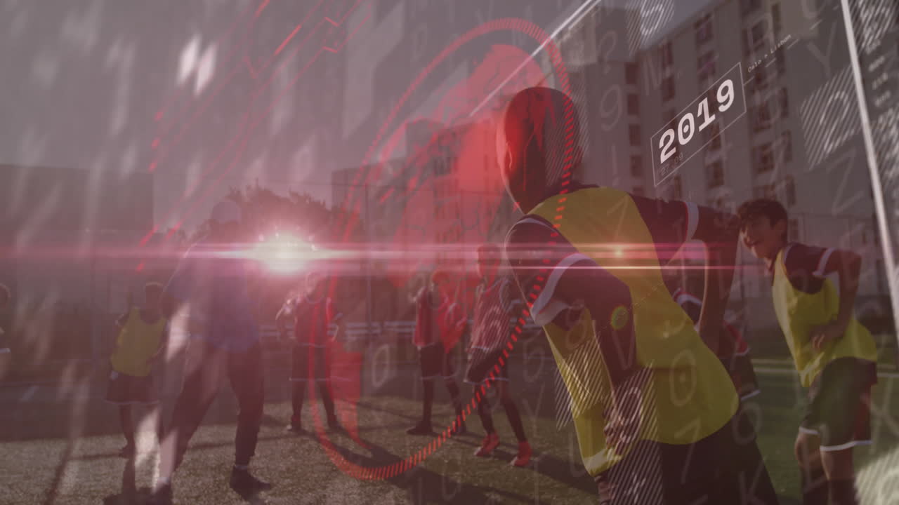 Coach and players practicing soccer on turf, using red sports analytics overlay with 2019 data