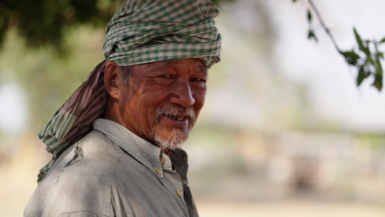Portrait of an elderly man with a headwrap smiling outdoors