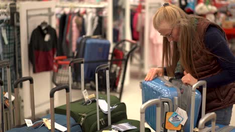 closeup of a woman looking through luggage in a store