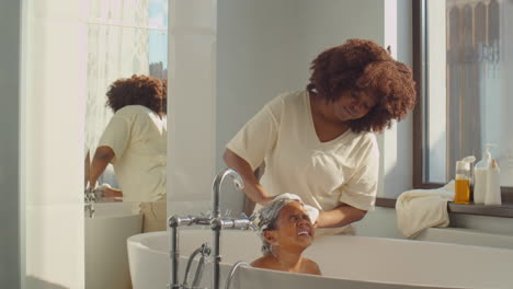 african american mother washing kid in bathroom