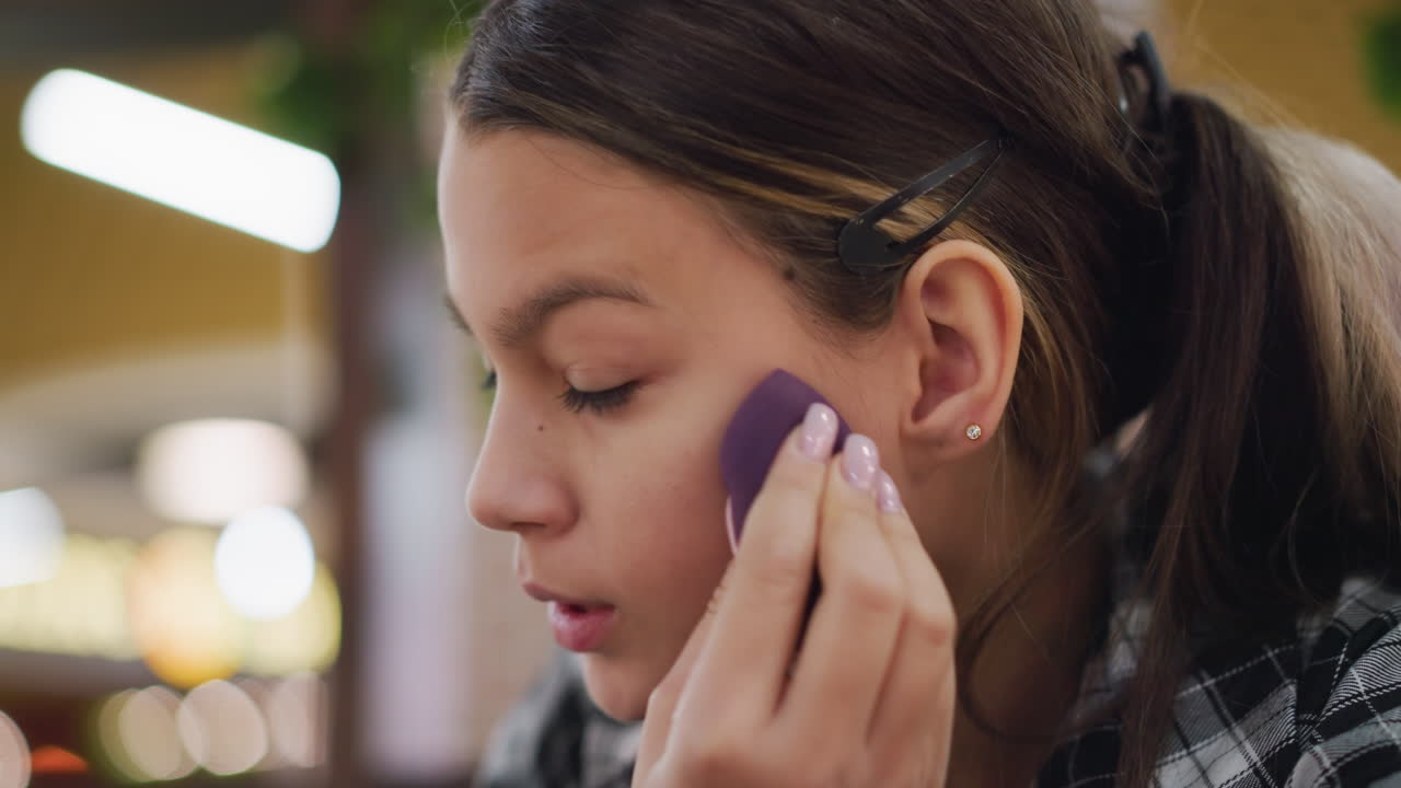 joven mezclando cuidadosamente el maquillaje facial usando esponja de belleza, asegurando una aplicación suave y uniforme, la expresión enfocada captura la rutina de belleza, el cuidado personal y la mejora impecable de la complexión