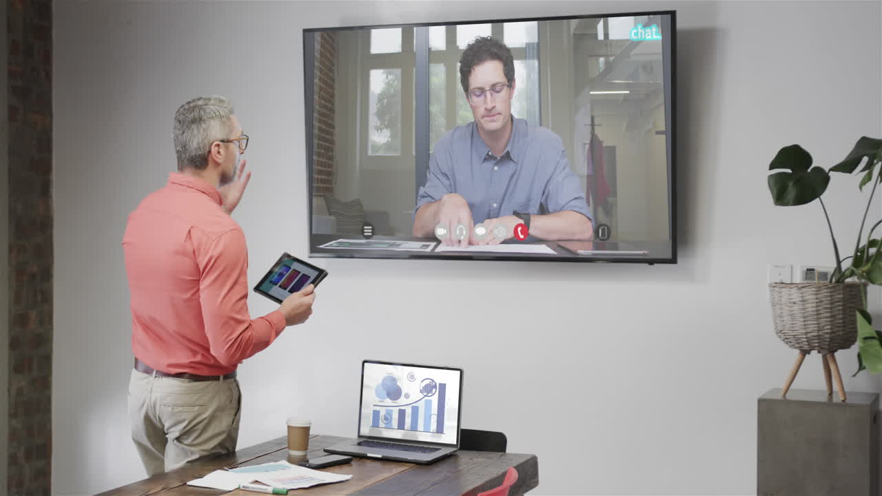 hombre de negocios caucásico en videollamada con un colega caucásico en la pantalla de televisión