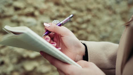 woman hands with a purple pen on the paper close up