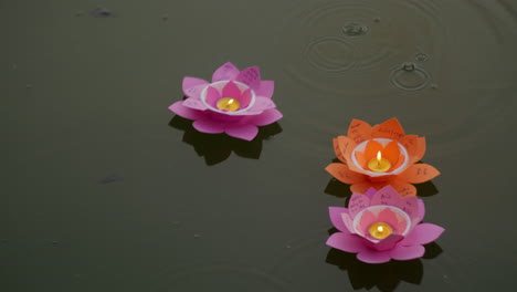 gota de lluvia cayendo sobre el papel luz vela forma de flor de loto flotando en el agua del río por la noche para el festival budista anual vesak celebración en el sureste de asia