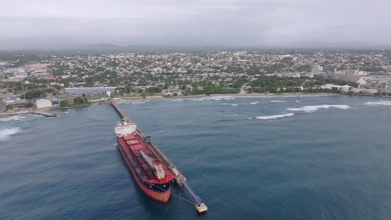 Aerial orbit shot of Fuel Ship docking at Port of Haina during cloudy day, Dominican Republic. process of supplying oil. Wide shot.