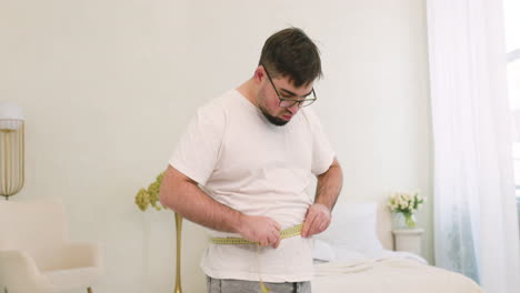 Boy-Measuring-His-Waist-In-The-Bedroom-1