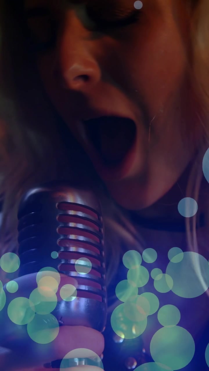 Vertical video: Female singer lifting vintage mic into frame, revealing lips and singing for power