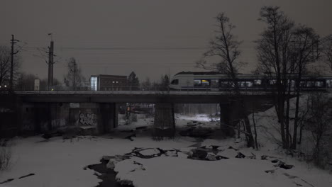 evening view of passenger train running across the bridge in winter city