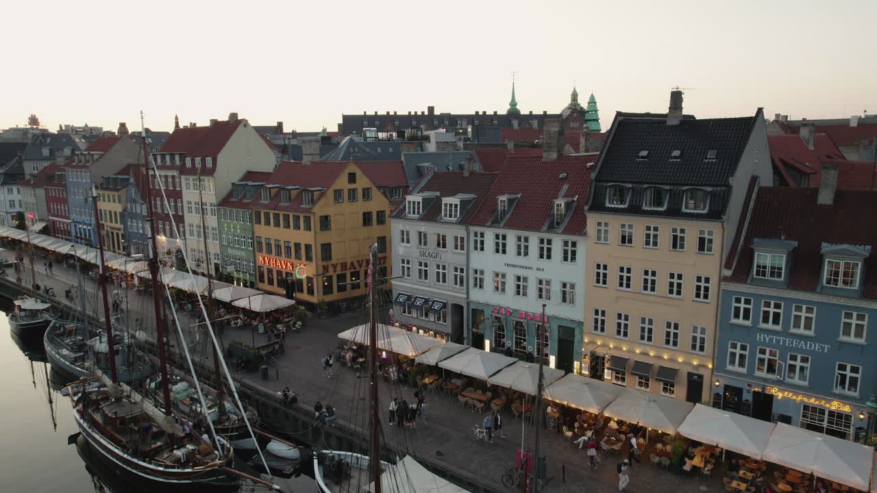 Nyhavn in Copenhagen during sunset, creating a warm and inviting atmosphere with people and boats lining the canal