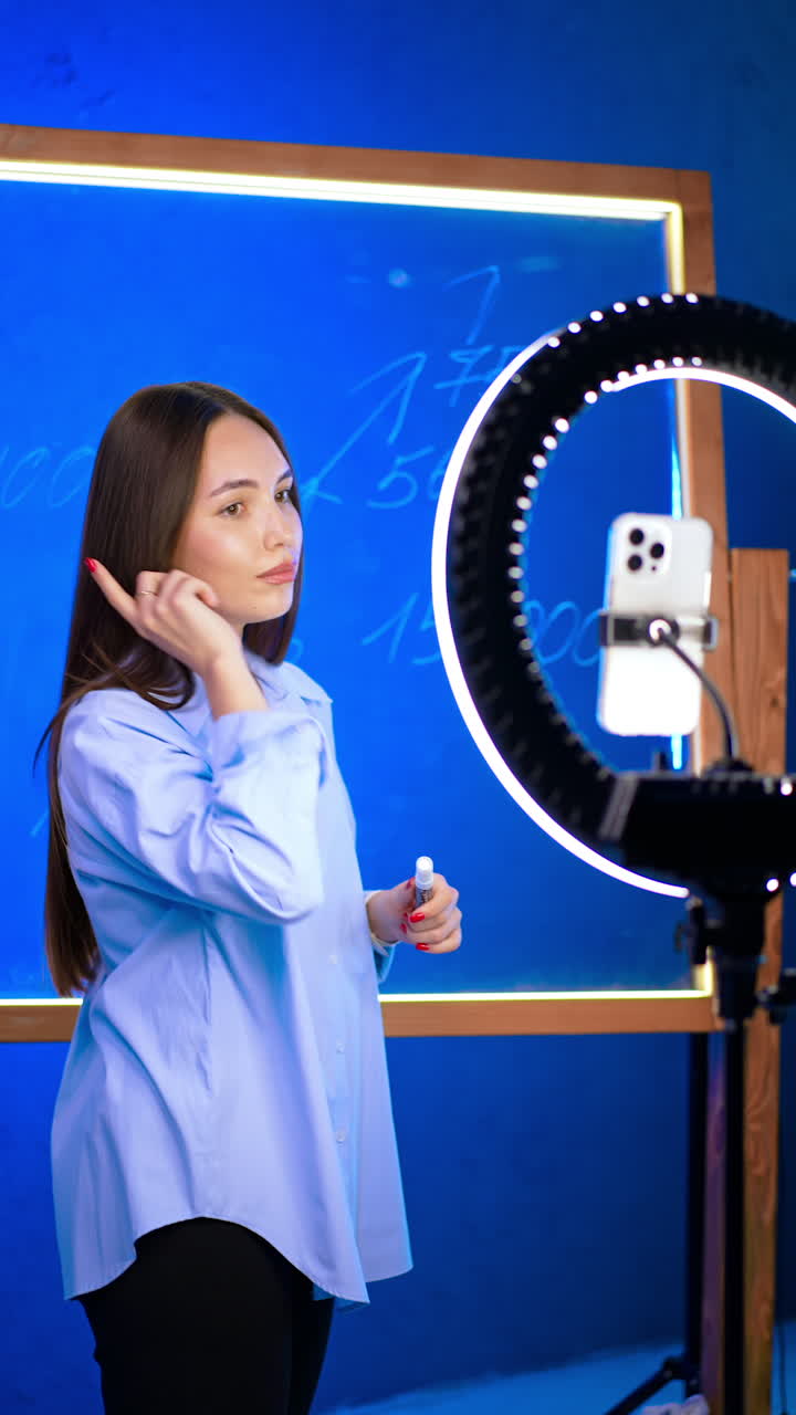 Dynamic talk in a modern space. A person gestures at a digital board showing percentages, using a ring light for better illumination