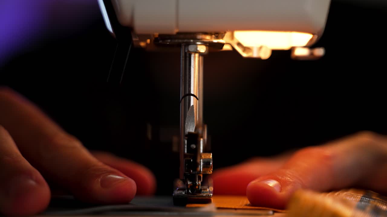 Front view of a sewing machine working in slow motion as a person holds the fabric in place