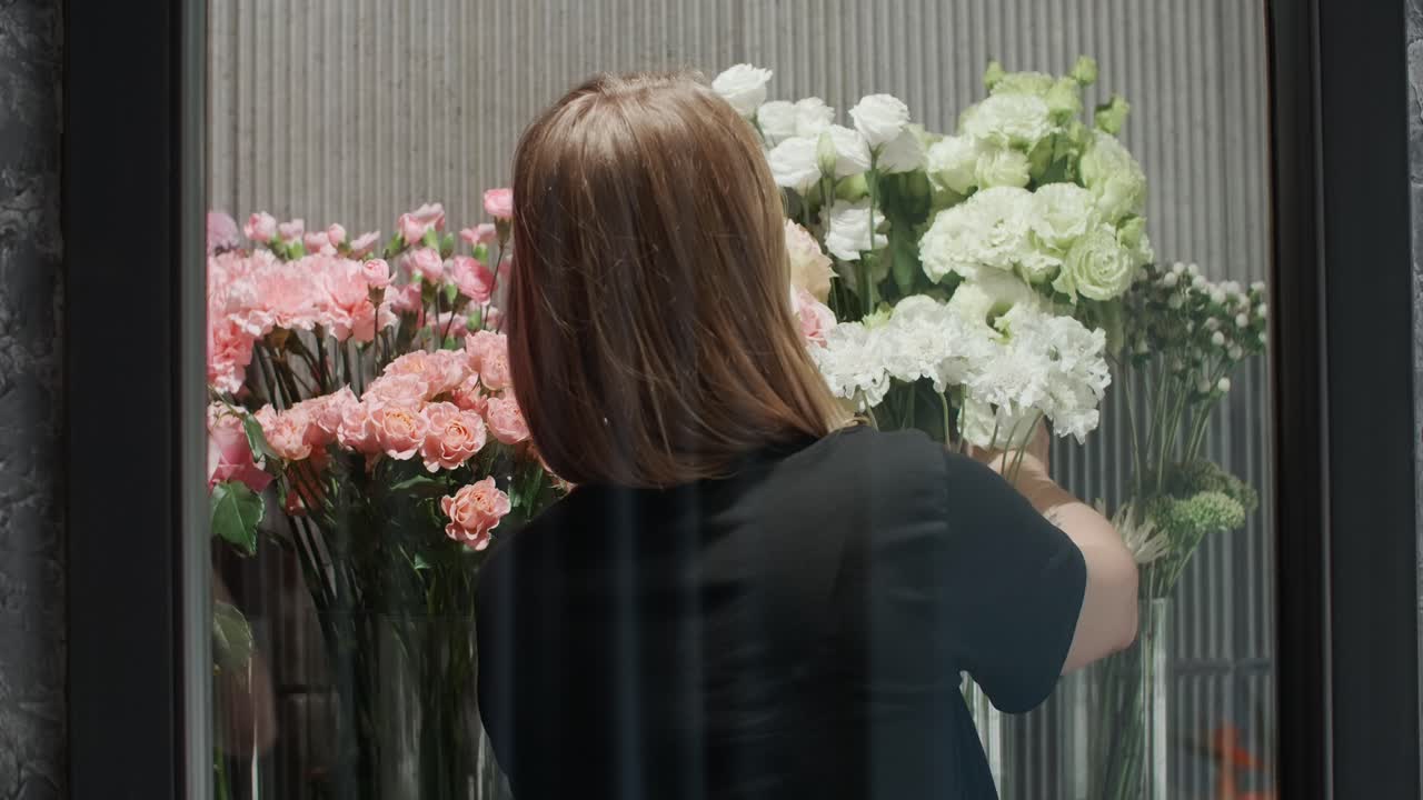 Woman arranging flowers in a flower shop display window