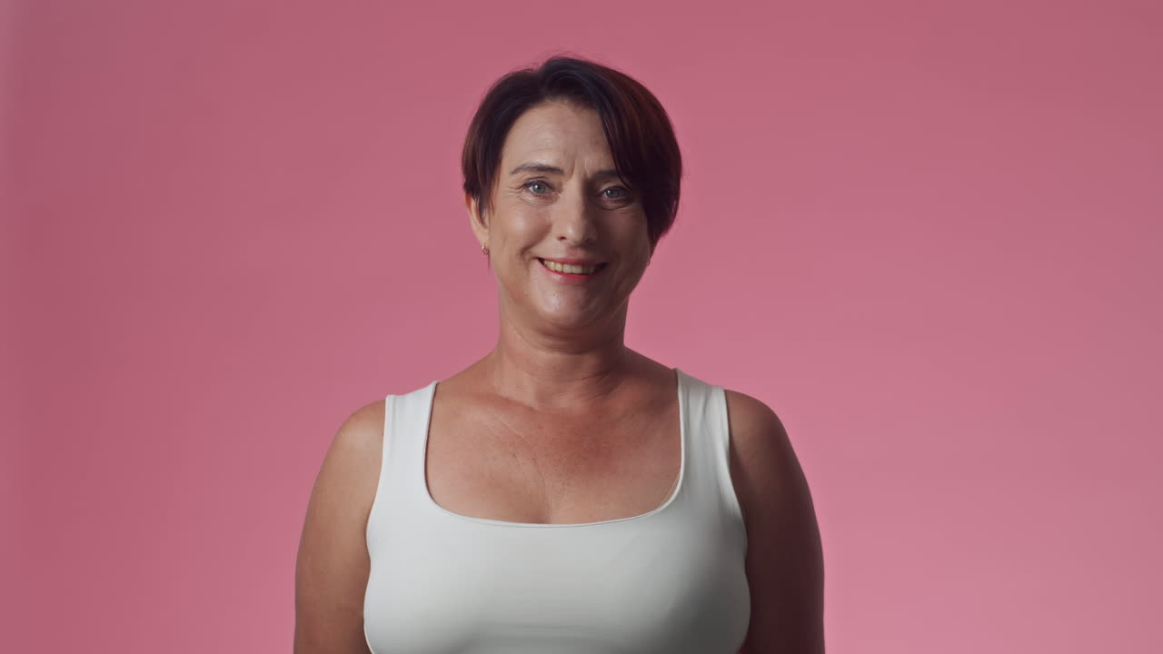Portrett av middelaldrende kvinne på rosa bakgrunn