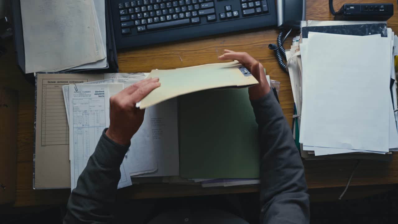 Office worker audits archive document files on desktop TOP DOWN view