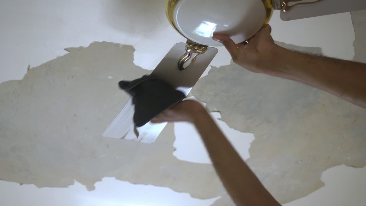 Closeup of South Asian man cleaning ceiling fan of bedroom