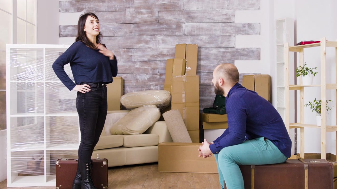 Couple Resting on Suitcases in Their New Unfurnished Apartment