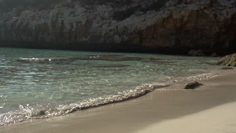 sunny view of caló des moro beach bathed by the mediterranean sea with some reflections in the water and cliff formations in the background in mallorca, balearic islands