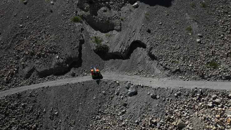 Cinematic downward angle drone shot of a Tuk Tuk driving on a small gravel path in the Gojal valley upper Hunza of the Gilgit Baltistan, Pakistan