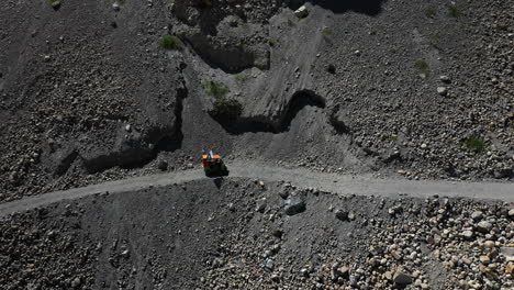 cinematic downward angle drone shot of a tuk tuk driving on a small gravel path in the gojal valley upper hunza of the gilgit baltistan, pakistan