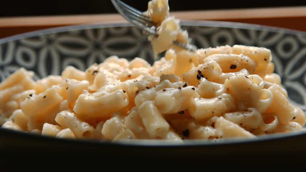 tenedor recogiendo bocados de delicioso queso de macarrón