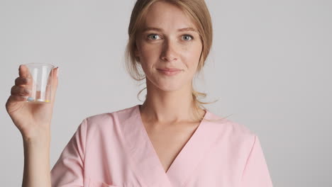 caucasian female doctor holding flask with pills.