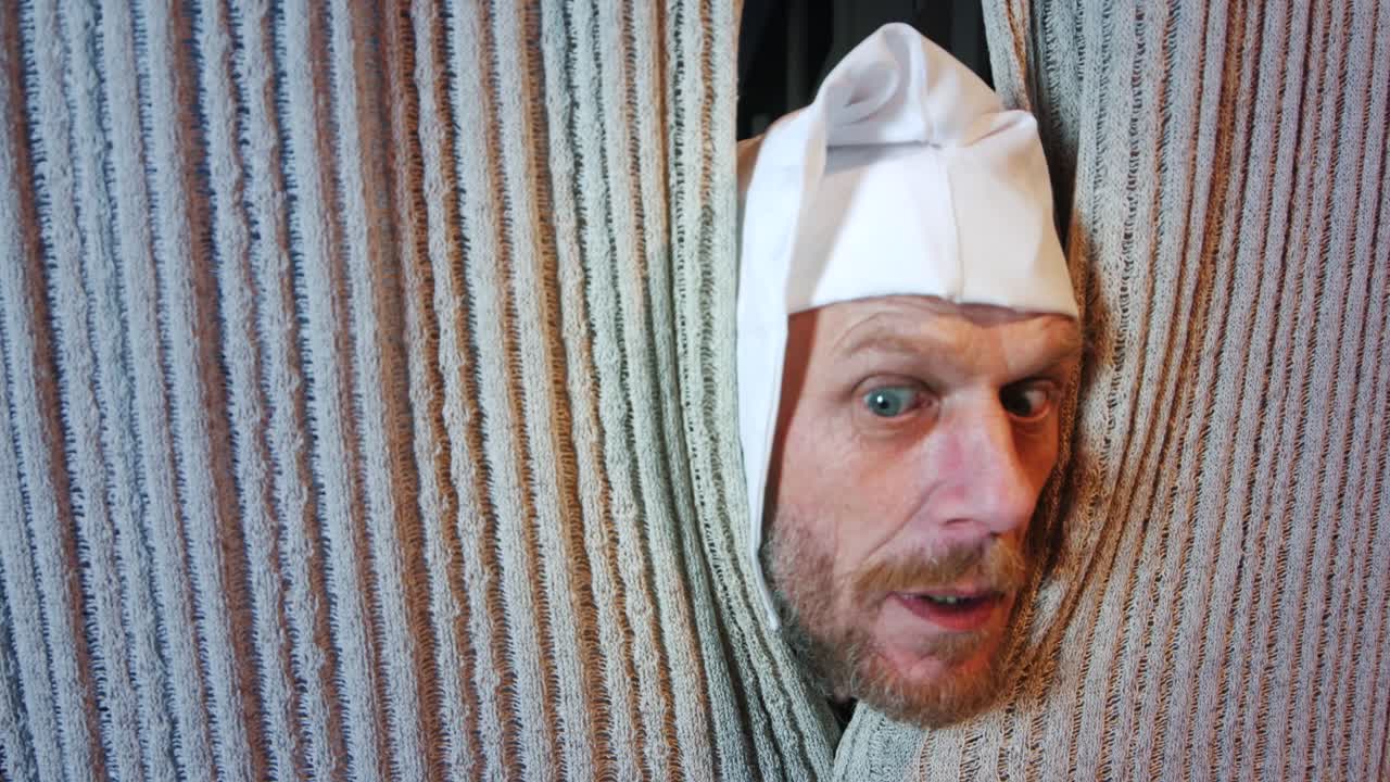 에베니저 스크루지는 찰스 디킨스의 크리스마스 캐럴에서 과거의 크리스마스 유령을 기다리며 침대 커튼을 들여다보고 있습니다.