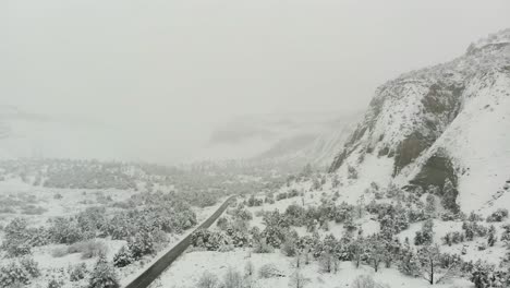 aerial shot of a beautiful snow covered road with mountains buried in the fog.