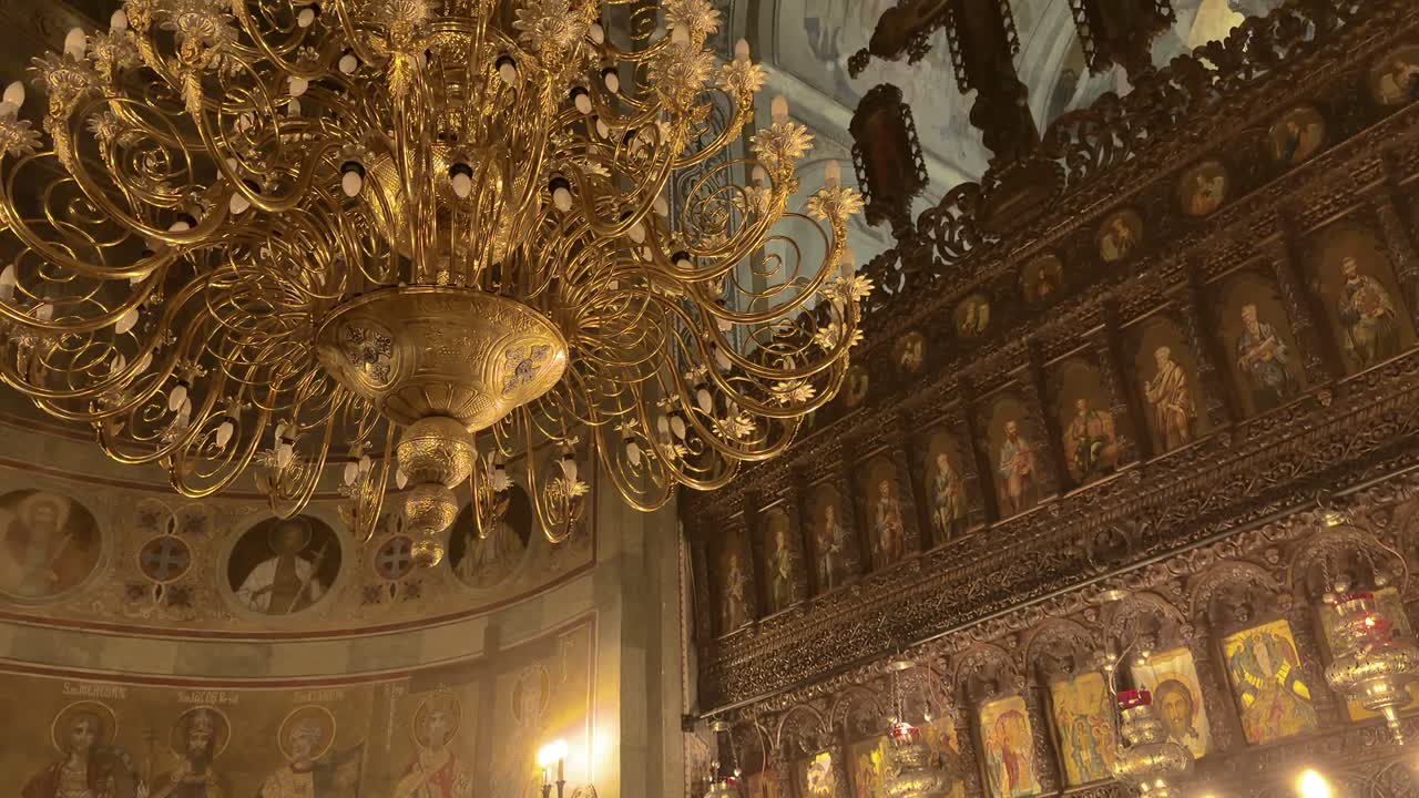 Interior ornamentado de iglesia rumana con lámpara de araña dorada e iconostasio detallado