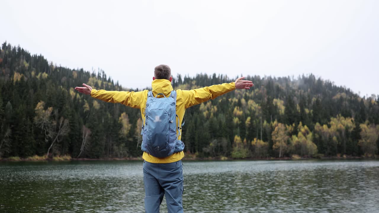 Man with arms outstretched by a lake