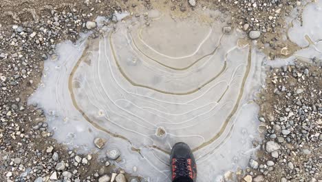 wide pov shot of stepping onto a frozen small puddle of water