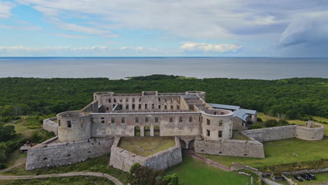 Steinarchitektur-Von-Mauern-Und-Türmen-Der-Ruinen-Des-Schlosses-Borgholm-Mit-Grünem-Wald,-Ruhigem-Meer-Und-Blauem-Himmel-Im-Hintergrund-In-Öland,-Schweden