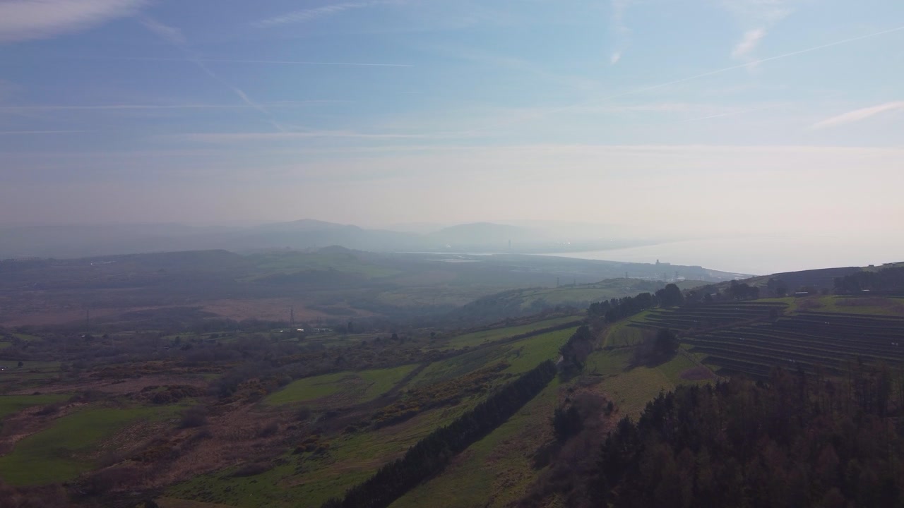 Hazy Landscape Aerial with Rolling Fields and Solar Panels on HIllside. Drone Footage from South Wales, UK.