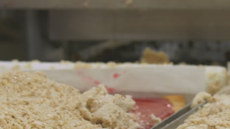 panning shot of busy workers preparing trays of baked desserts