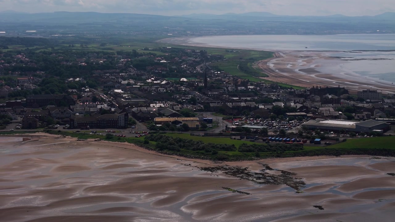 Troon, South Ayrshire, Szkocja, o świcie, ukazujące piaszczystą plażę, nadmorskie miasto, linię brzegową i spokojne poranne światło wzdłuż zatoki Firth of Clyde, kinowy widok z lotu ptaka z panoramowaniem.