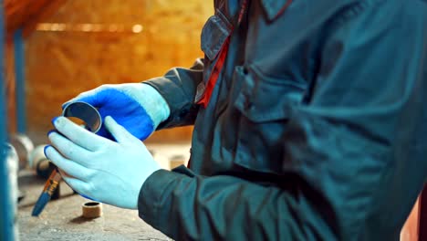 male worker uses a brush to paint a circle tool for a special section of a machine.