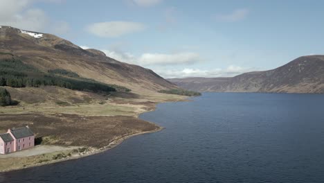 Aerial-view-of-the-famous-Pink-House-on-the-shores-of-Loch-Glass-in-the-Scottish-Highlands-on-a-sunny-spring-day