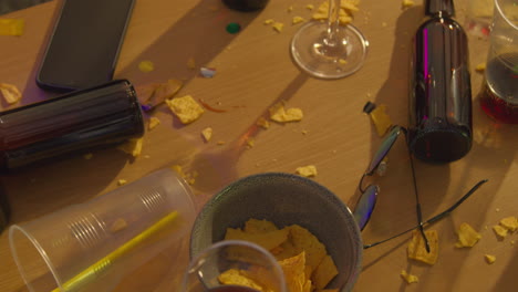 close up of messy table covered with empty wine glasses and beer bottles after house party