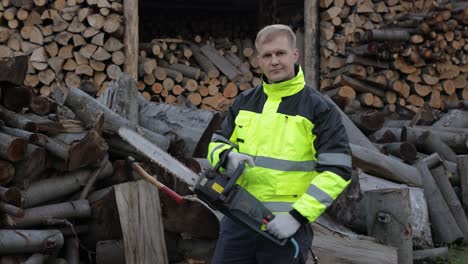 lumberjack in reflective jacket. man woodcutter with electric chainsaw. show ok sign. sawmill