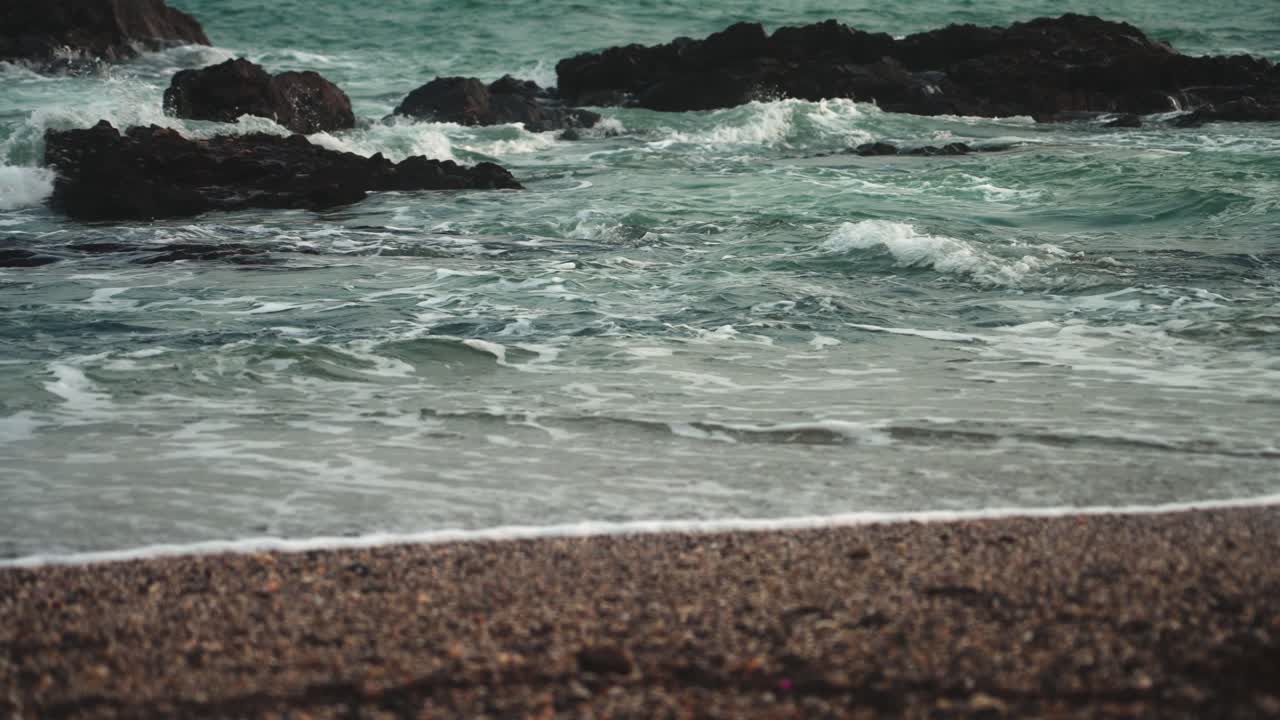 olas en cámara lenta en una playa rocosa y arenosa en cámara lenta