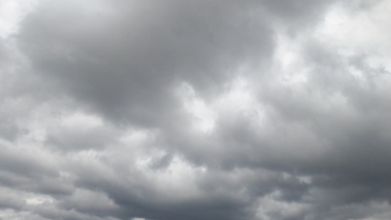 Rarely appearing blue sky from behind the grey clouds. Overcast horizon from low angle view. Timelapse.