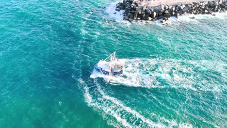 aerial view of trawler near rocky coastline