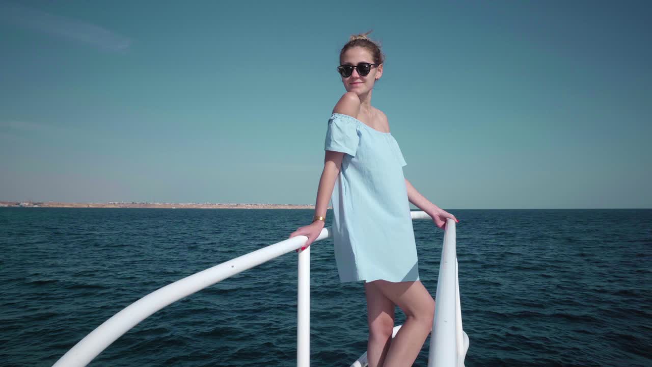 파란색 드레스와 선글라스를 입고 요트에 탑승한 젊은 섹시한 백인 여성의 초상화 - 휴가, 자유, 빛 여름의 개념 - 배경에 파란 바다