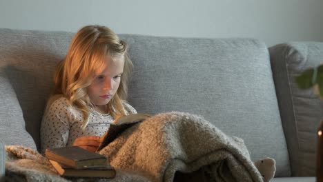 niño pequeño leyendo un libro viejo en un cómodo sofá