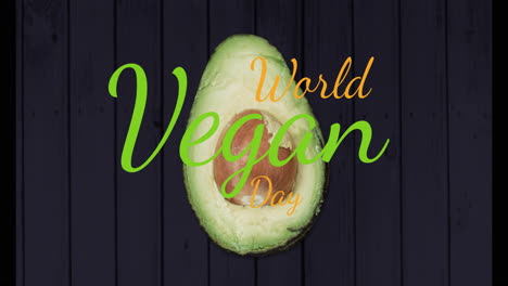 avocado with world vegan day text over dark wooden background